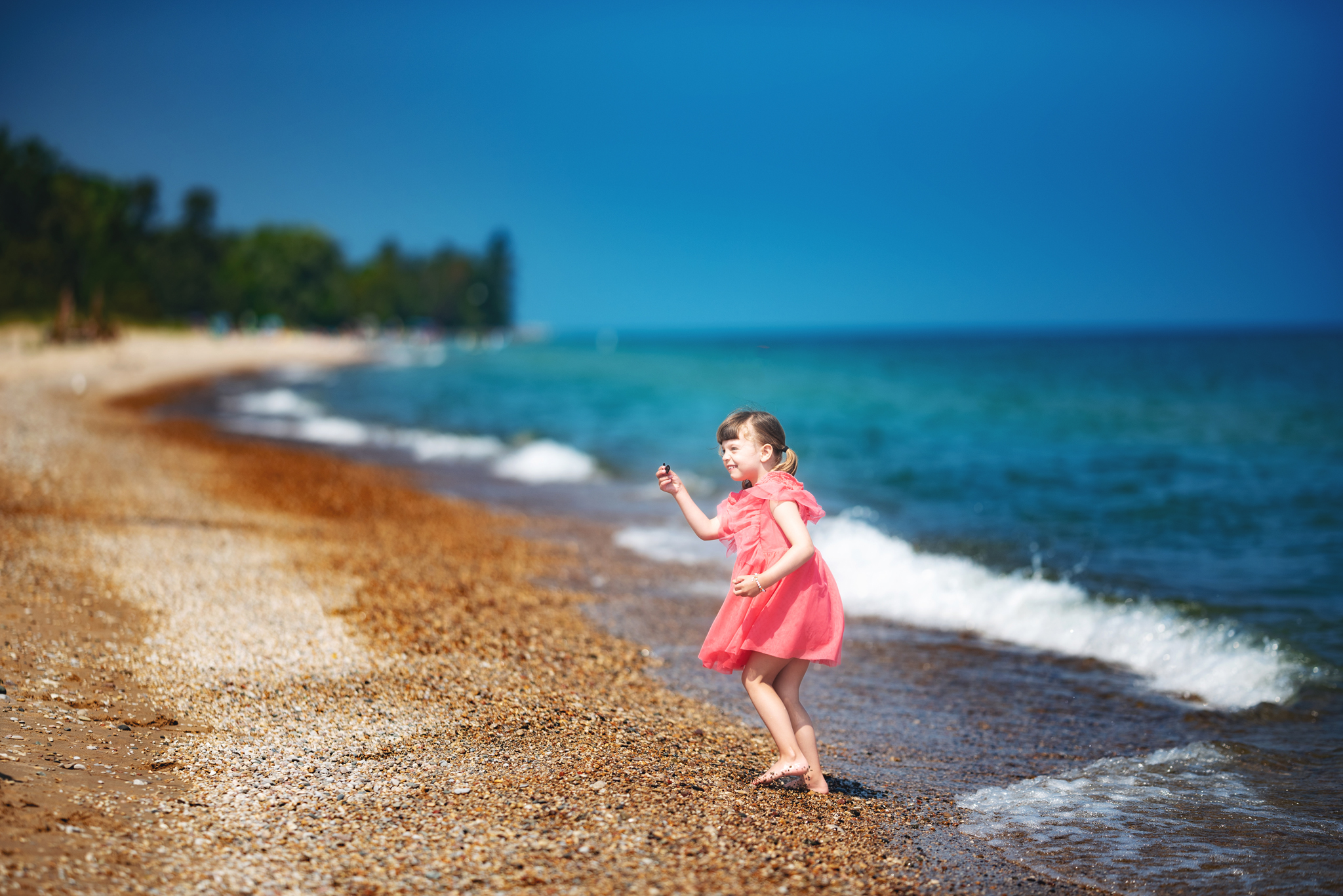 Little girl looking for stones along Lake Huron during family photo session.