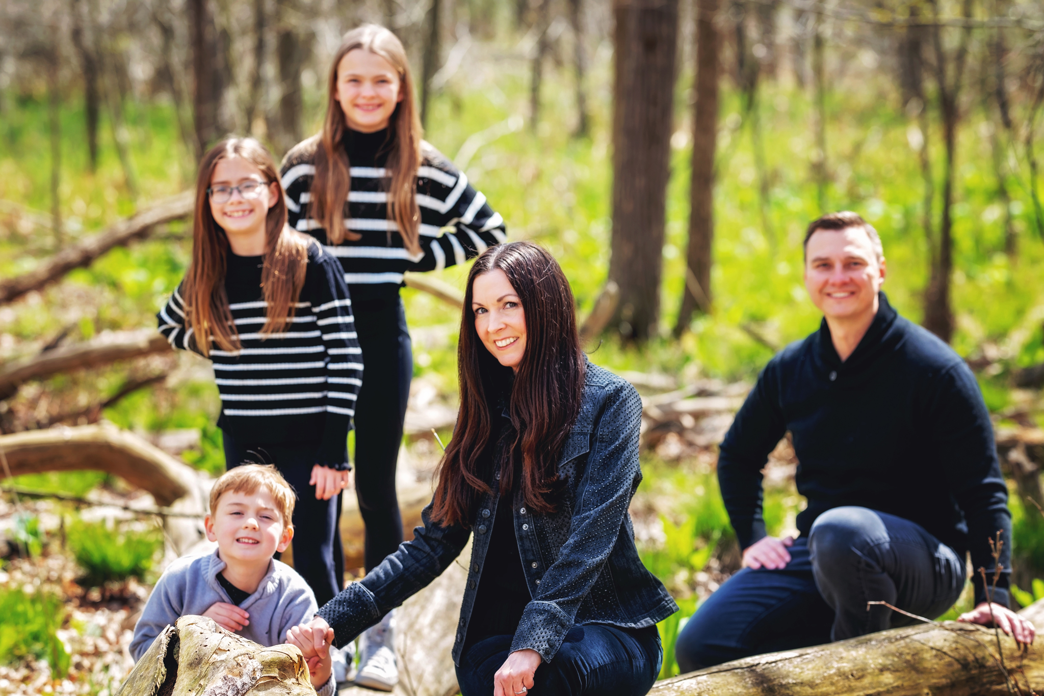 Family enjoying spring green forest during their portrait session in Northern Michigan.